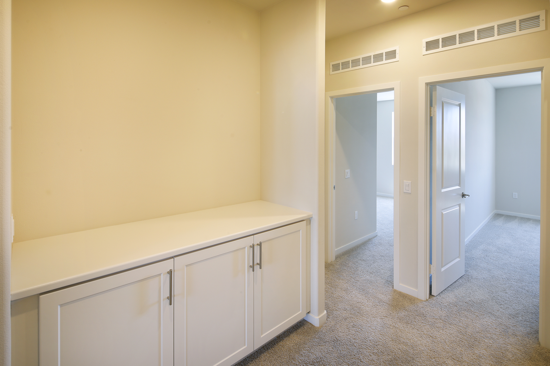 A hallway with white cabinets.