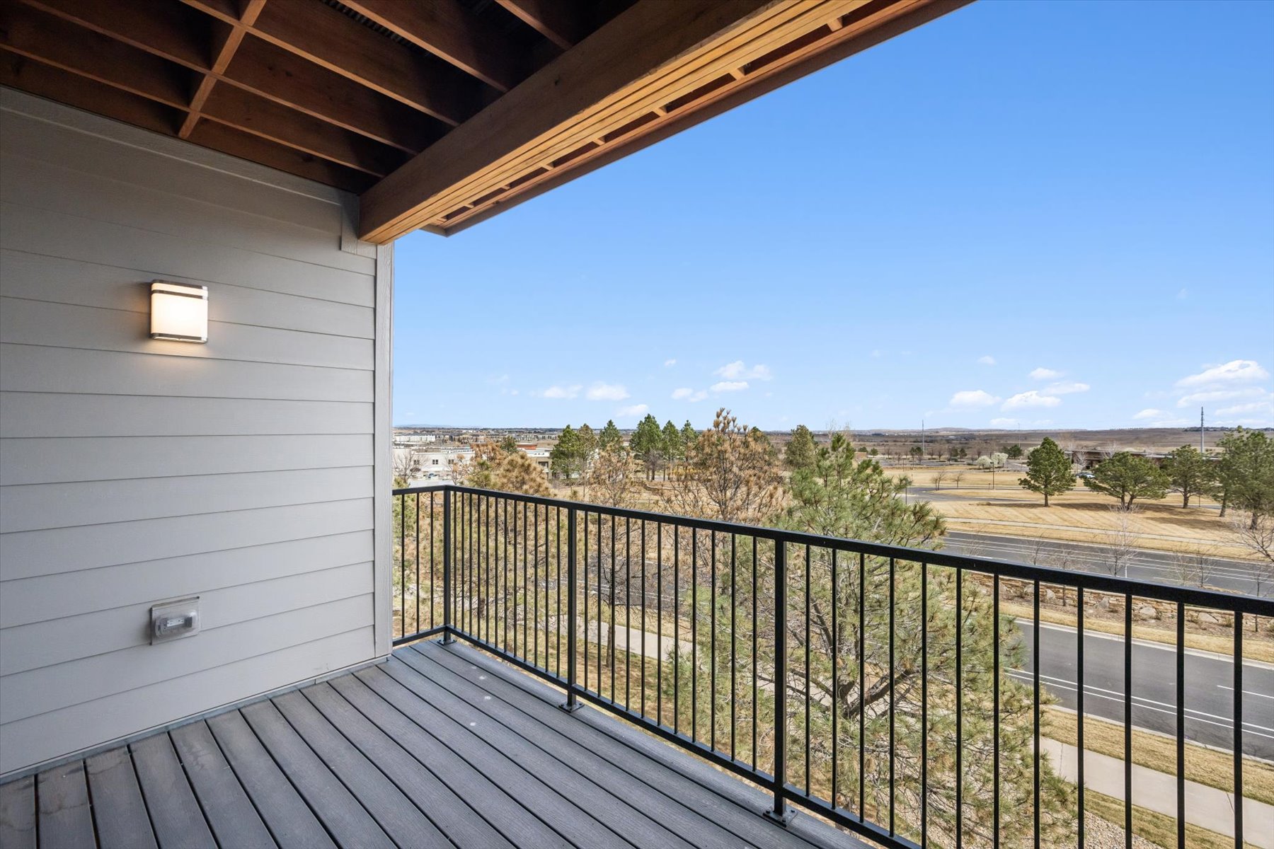 A deck with a view of a field and trees.