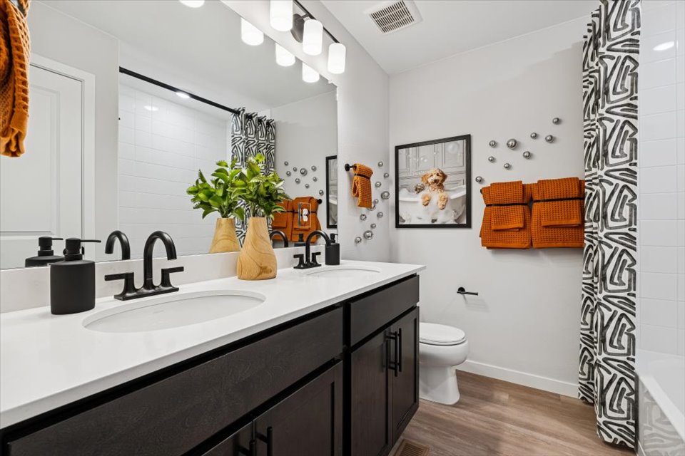 A bathroom with a sink toilet and a mirror.