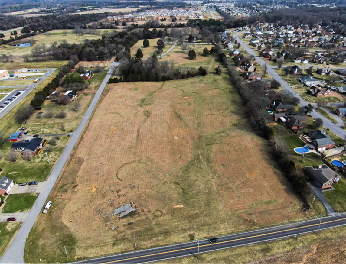 A road with a field and houses.