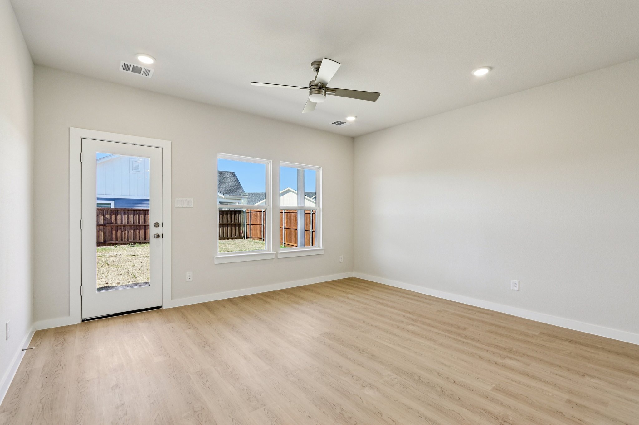 A room with a wood floor and a ceiling fan and a wood floor.