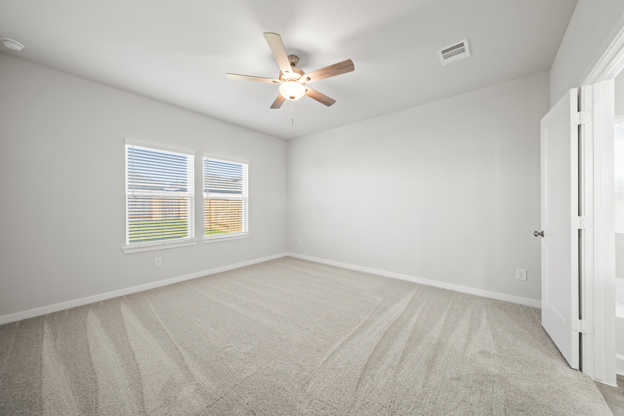 A room with a ceiling fan and a carpet.