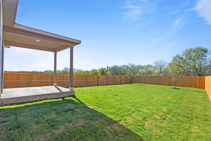 A backyard with a fence and a lawn.