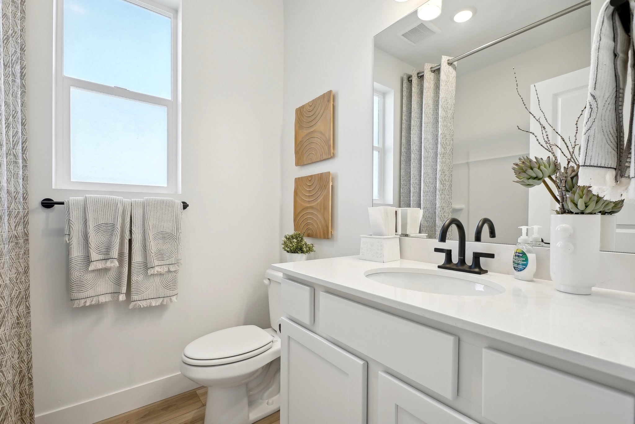 A bathroom with a sink toilet and mirror.