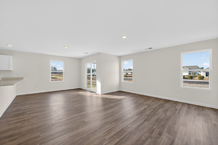 A large empty room with a wood floor and a large window.