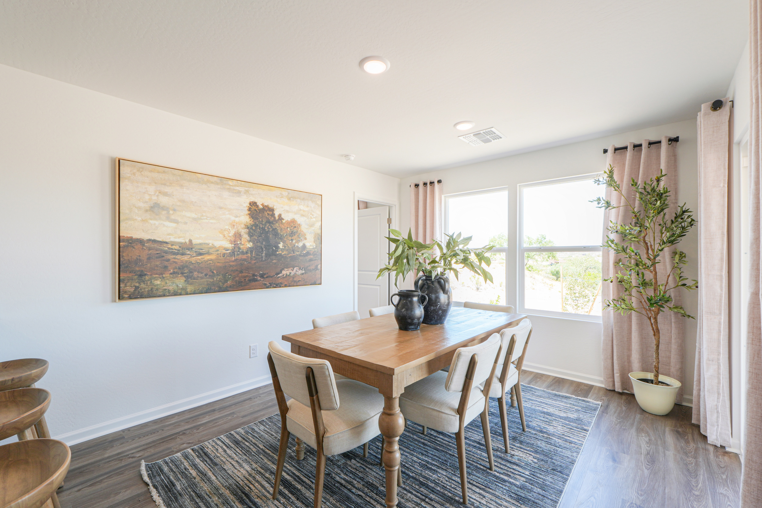 A dining room table with chairs and a painting on the wall.