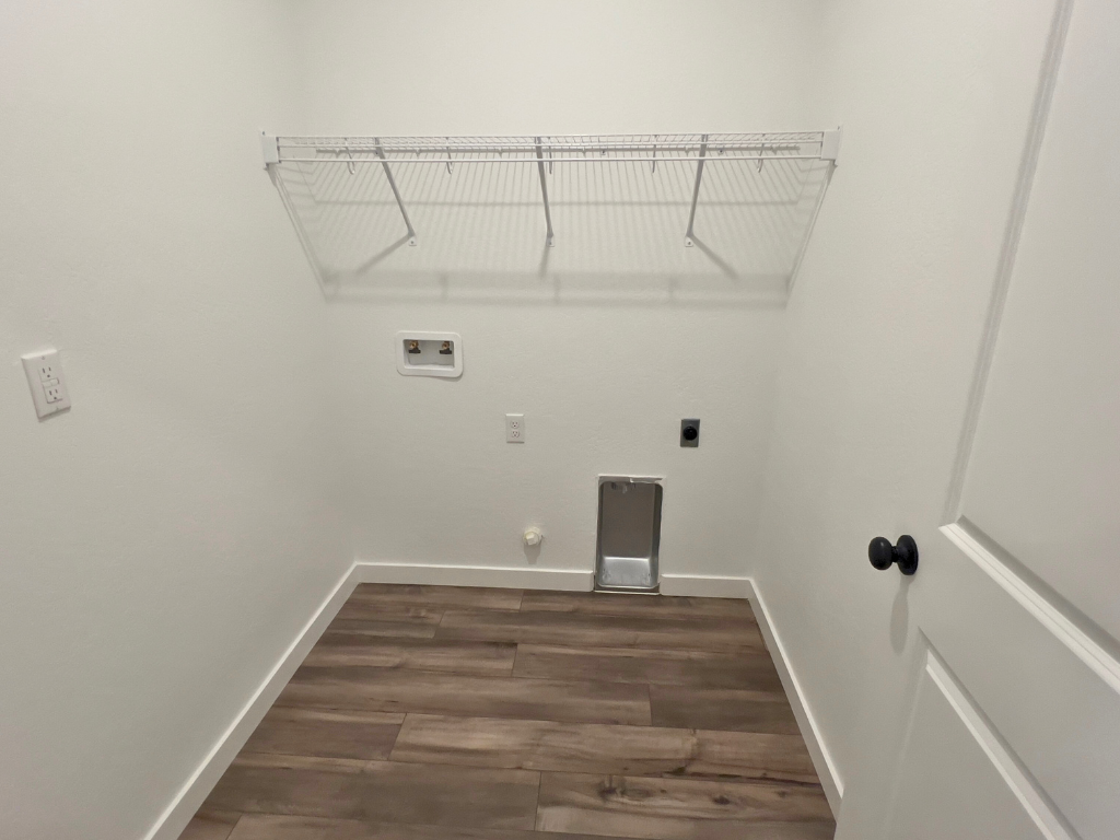 A room with a wood floor and a white wall with a white door.